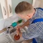 Worker Pressing Plunger In Sink Plombier débouche un évier avec une ventouse