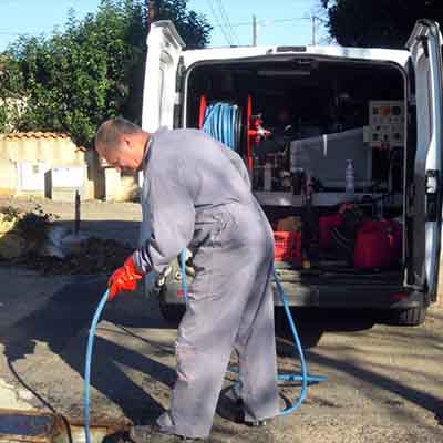 plombier qui débouche une canalisation avec une hydrocureuse